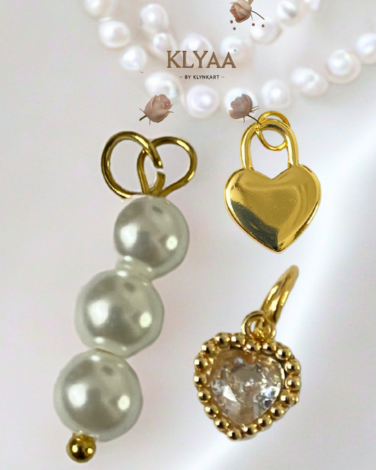 Close-up of three detachable charms – pearl, gold heart, and crystal heart – for the Golden Trinity Chain by KLYAA