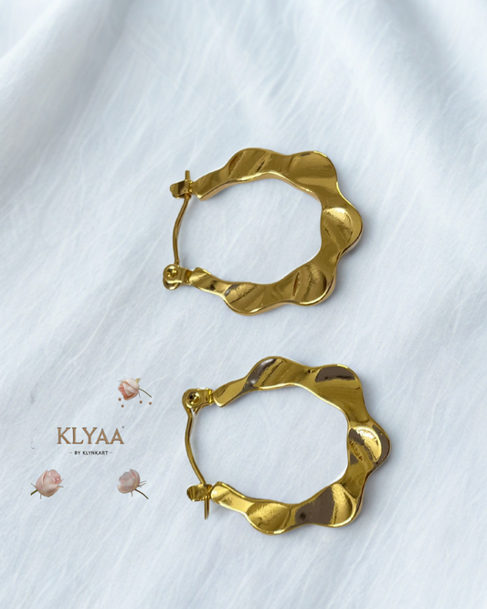 Ripple design sculpted anti-tarnish gold hoops by KLYAA displayed on textured surface
