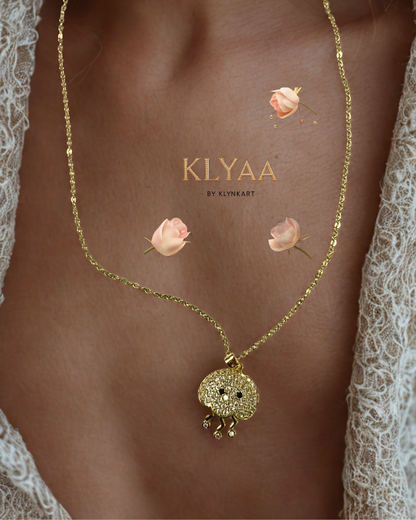 Gold-plated chain with a sea-creature-inspired pendant featuring crystal stones and three delicate danglers, worn on neck.