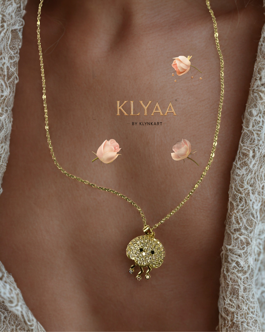 Gold-plated chain with a sea-creature-inspired pendant featuring crystal stones and three delicate danglers, worn on neck.
