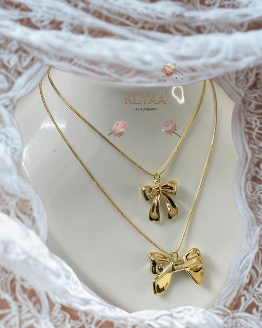 Double bow gold necklace worn with a deep neckline – elegant and luxe design